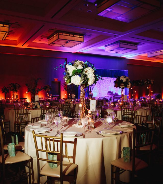 Decorated banquet hall with served round table with hydrangea centerpiece and chiavari chairs